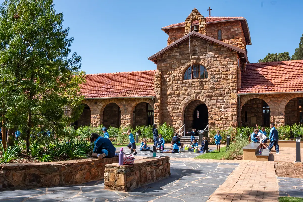 The quad and stone chapel building at St Luke's College, with children at play