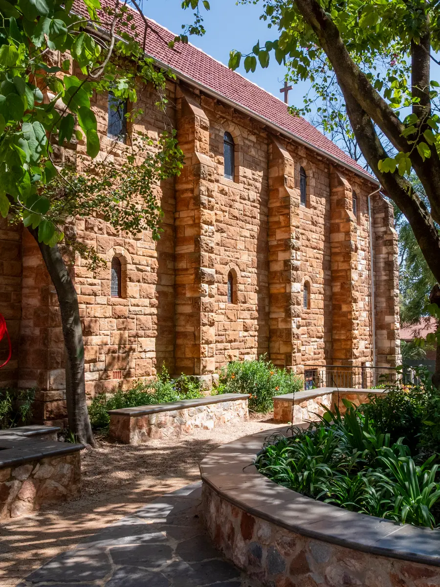 A stone path through the garden to the sandstone chapel, framed by old trees