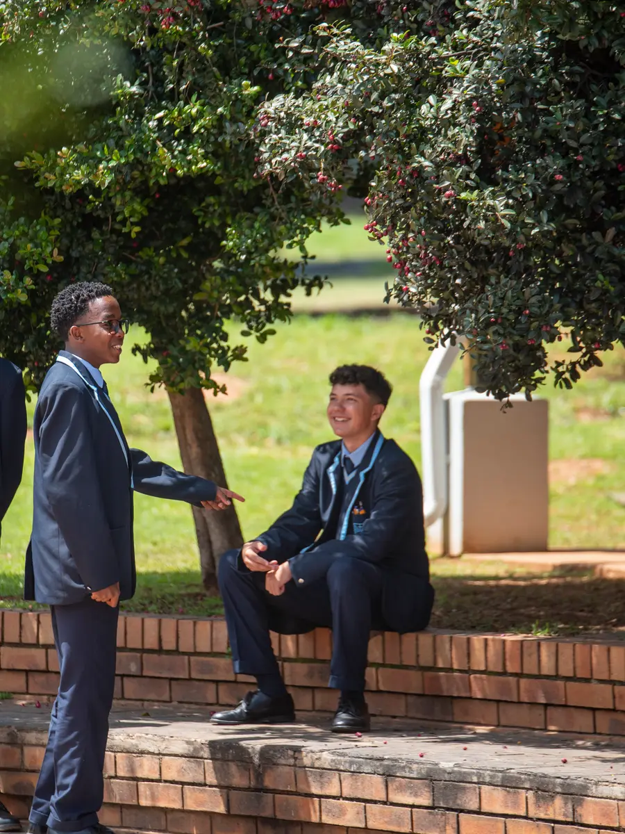 High School boys talking together on the steps beneath a tree