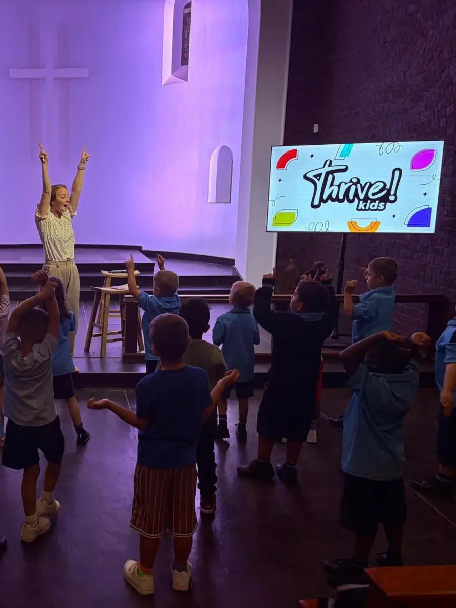Young children singing with their arms raised during worship in the chapel
