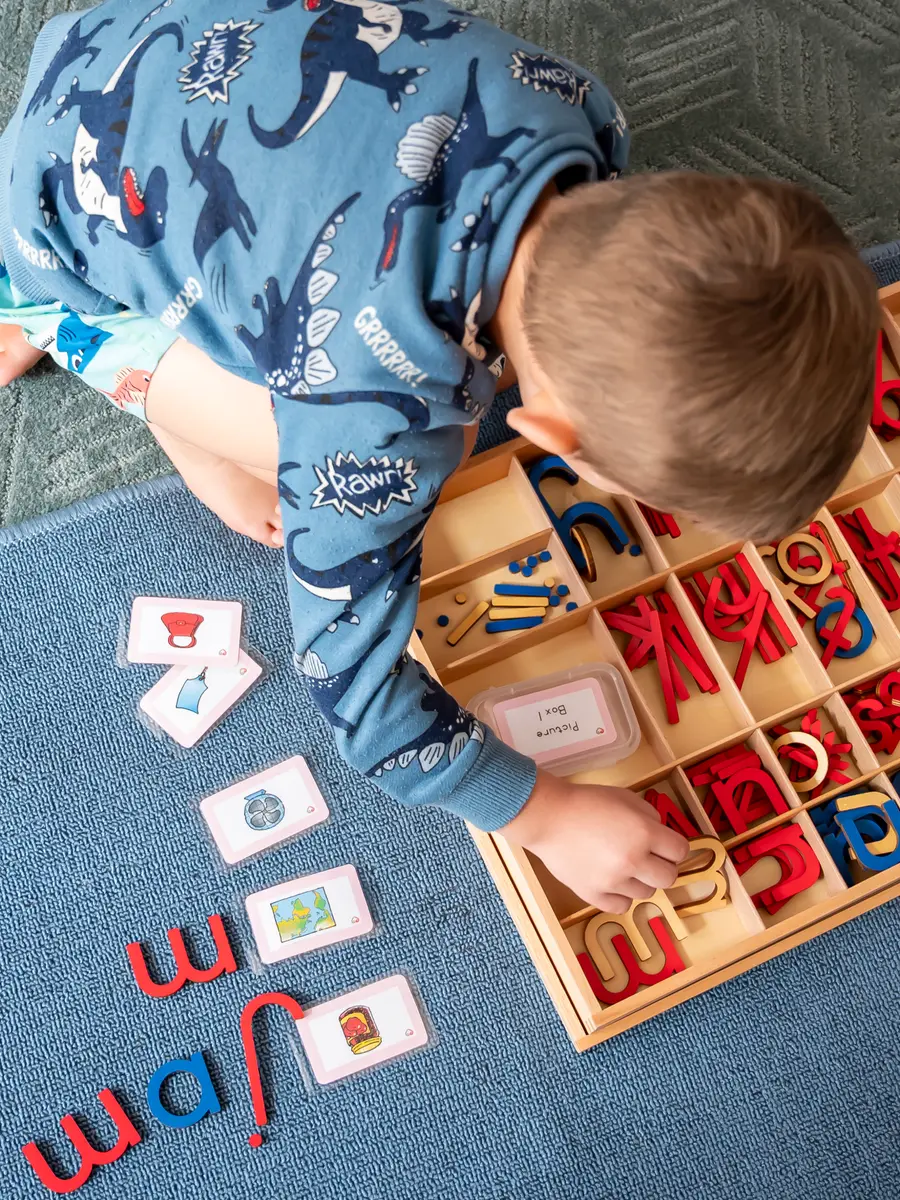 A preschool child spelling words with a wooden moveable alphabet