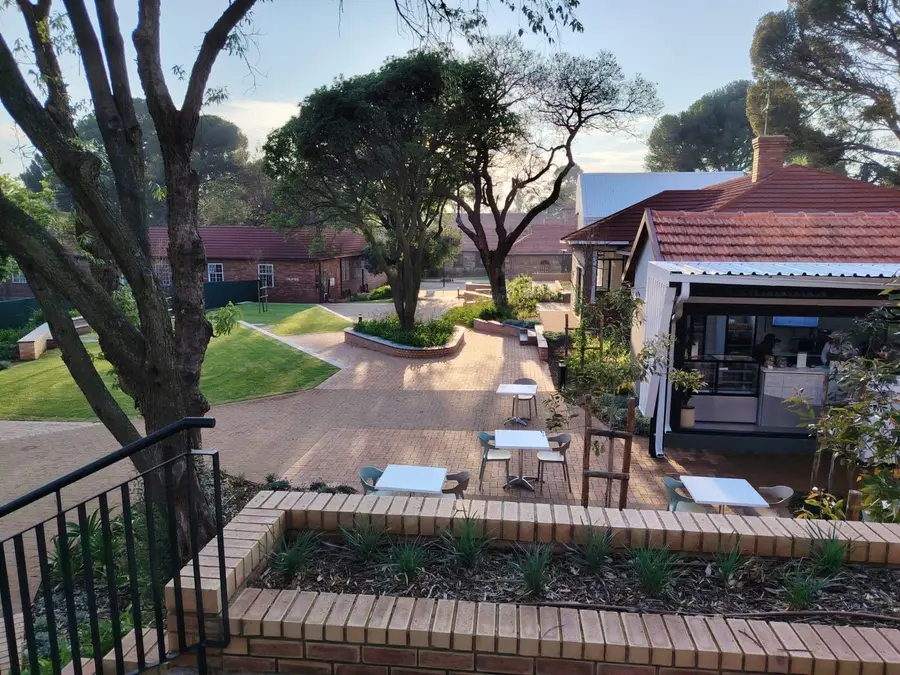 Lawns, old trees and outdoor tables in the gardens between the stone buildings