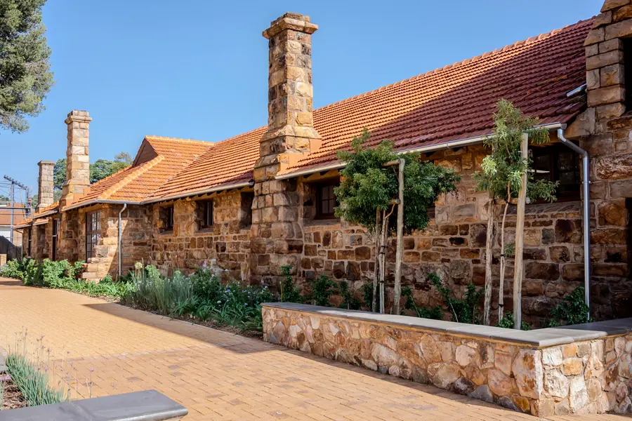 Stone buildings with red tiled roofs and a planted garden