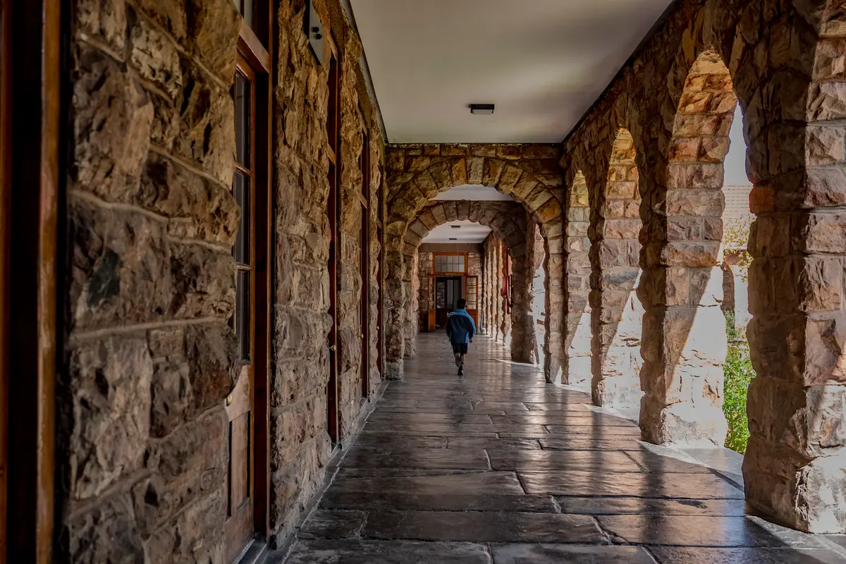 A stone arched colonnade on the heritage campus, with a child walking at the far end
