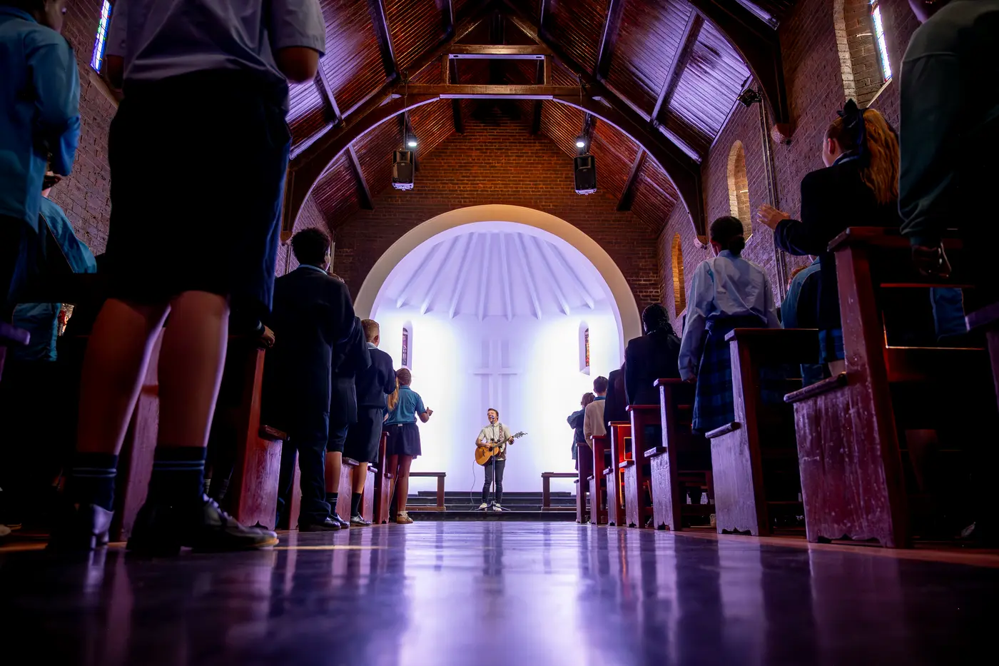 Students gathered for worship in the historic chapel, lit from the arched window