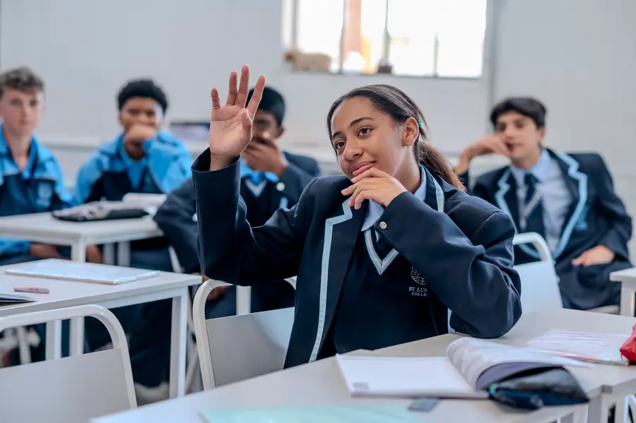 High School students laughing together in class, one waving