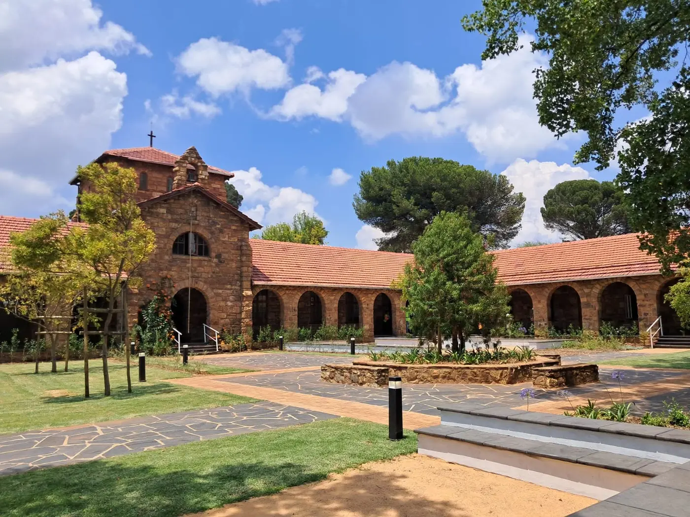 The quad and stone bell tower of the Herbert Baker building under a blue sky