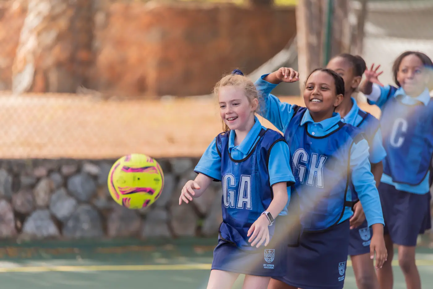 Preparatory School netball players laughing as a ball flies past