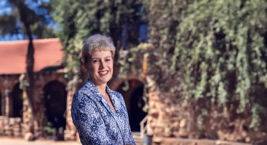 Colleen Traviss-Lea standing in front of the ivy-covered stone buildings