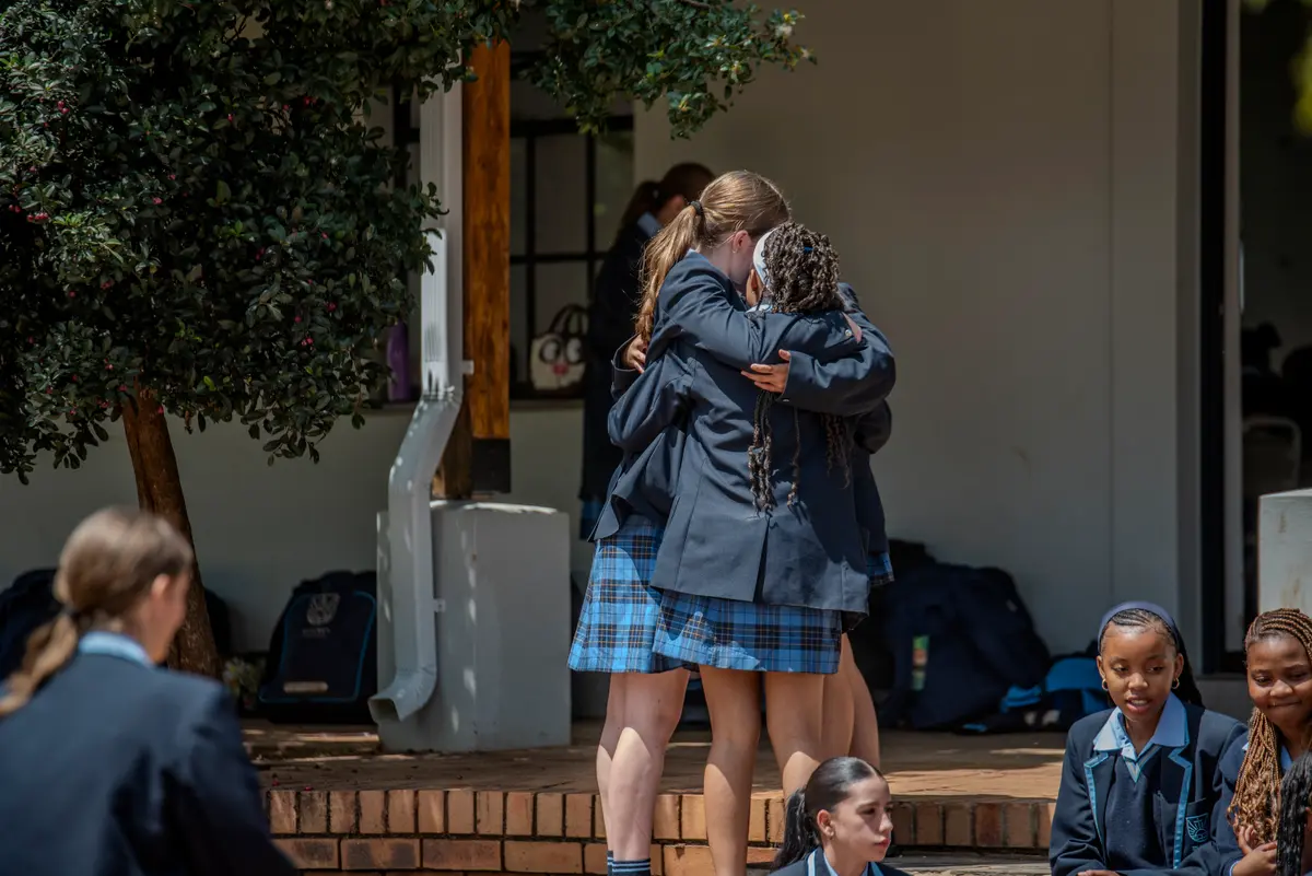 High School students hugging and chatting on the stoep between classes