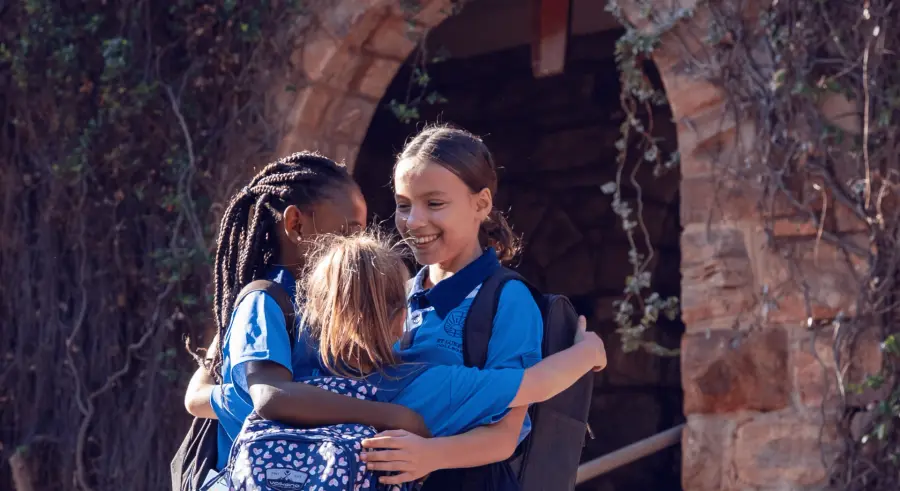 Two girls hugging under a stone archway