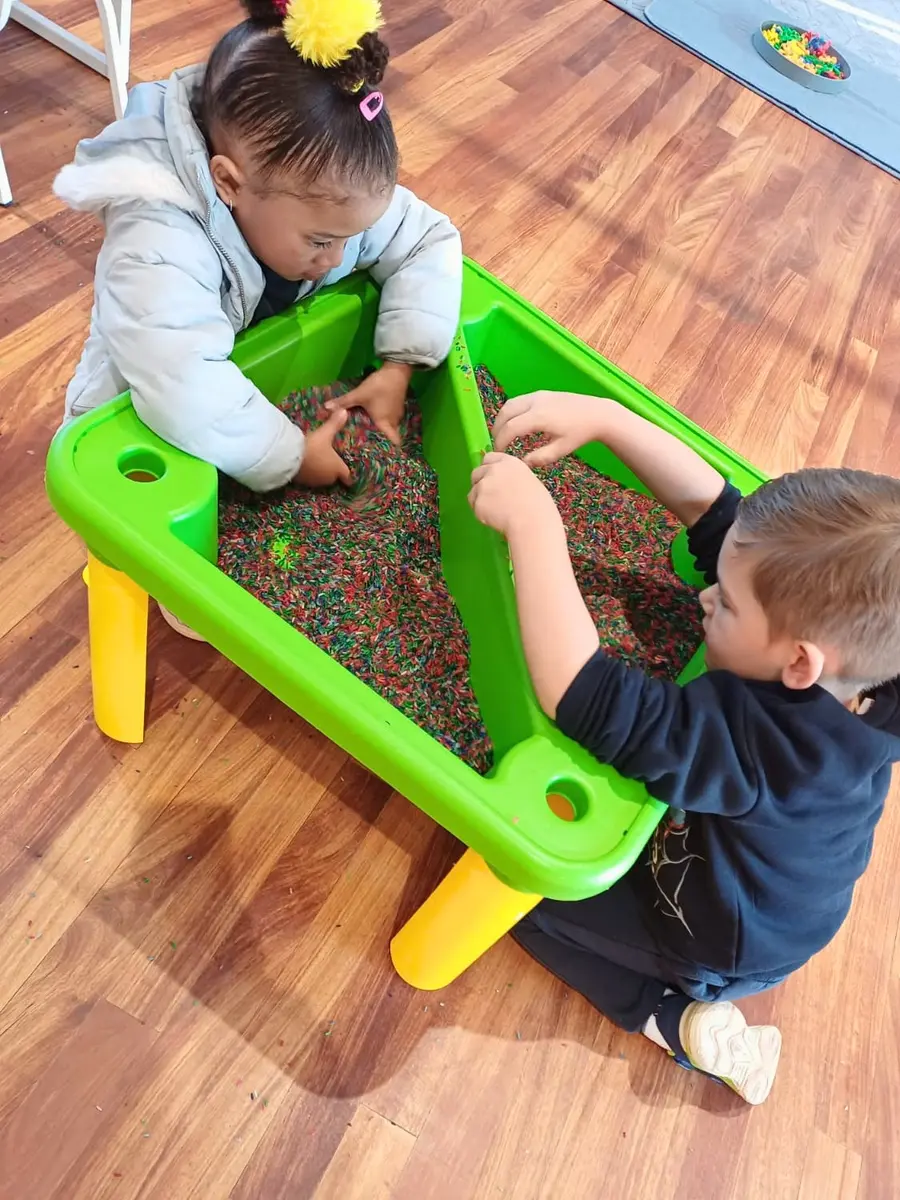 Two young children playing together at a sensory table