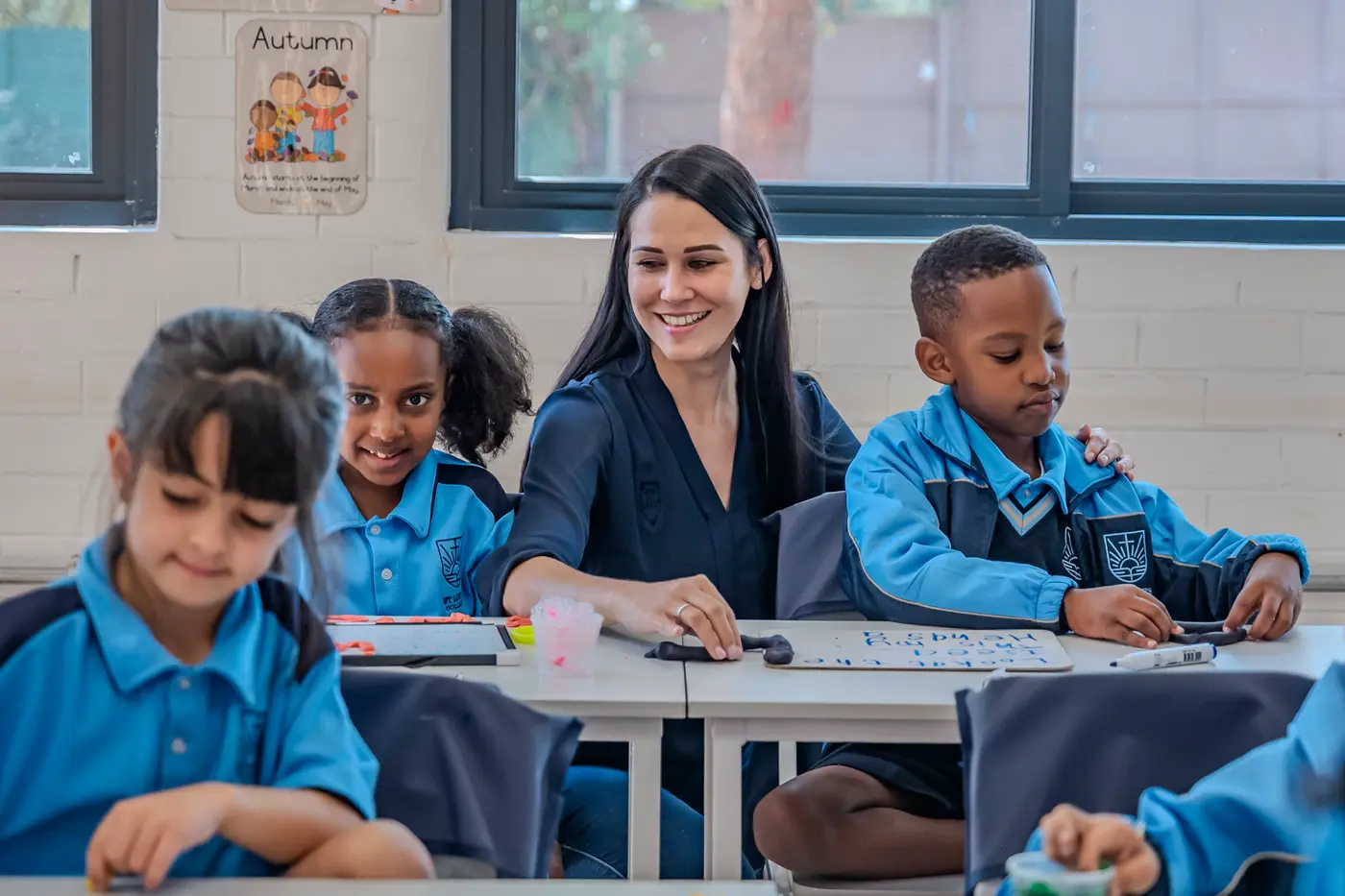 A teacher smiling with her Grade 1 class as they work at their desks