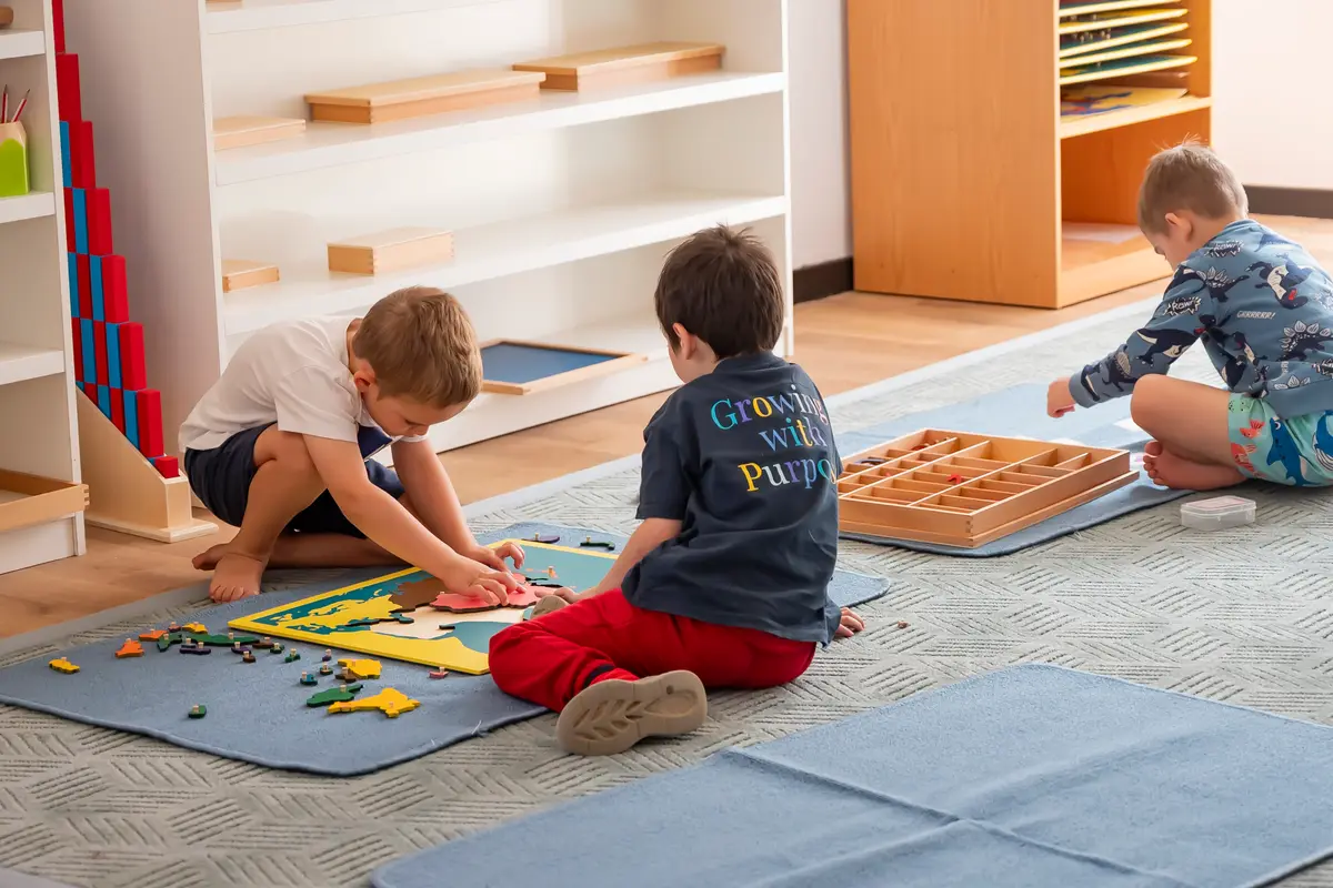 Preschool children working with Montessori materials on mats in a bright classroom
