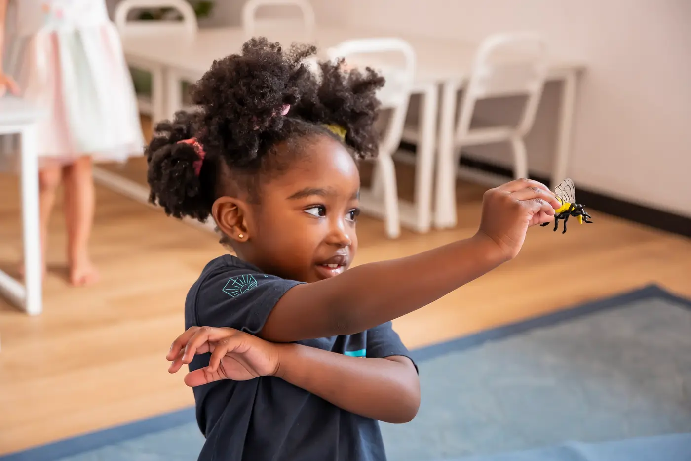 A preschool girl holding up a small toy animal and smiling